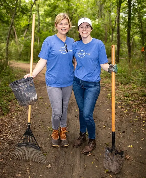 Two volunteers holding tools in the woods for tree planting